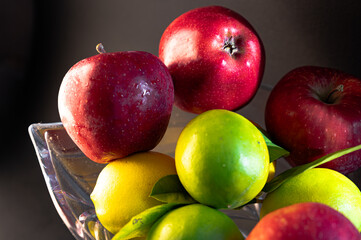 Still Life with Red Apples and Lemons in a Glass Vase on Black Background