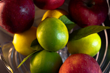 Still Life with Red Apples and Lemons in a Glass Vase on Black Background