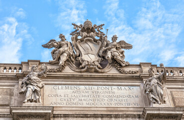 Obraz premium Rome, Italy, Trevi Fountain. Architectural detail of a historic building featuring ornate sculptures and inscriptions under a bright blue sky, showcasing classic design elements and craftsmanship