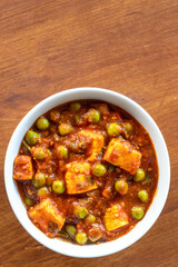 Homemade spicy matar paneer curry, cottage cheese, tomato, garden peas, served in bowl. Top view.