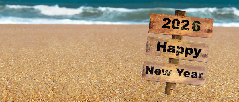 2026 happy new year writted on a wooden sign post planted on the sand on a beach with waves on the sea background