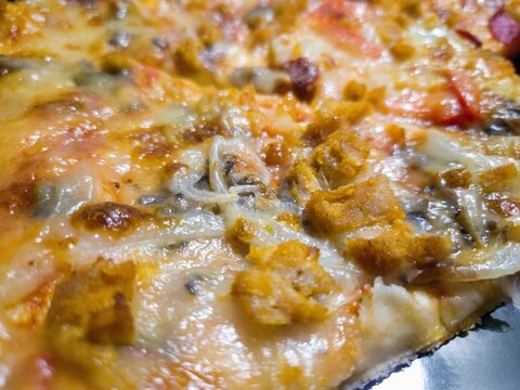 Close-up of freshly baked pizza with melted cheese, onions, mushrooms, and crispy toppings.