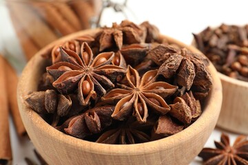 Mulled wine spices. Anise stars in wooden bowl and cinnamon sticks on white table, closeup
