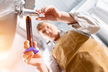 Caucasian male brewer testing beer quality at brewery, craft brewery with fermentation