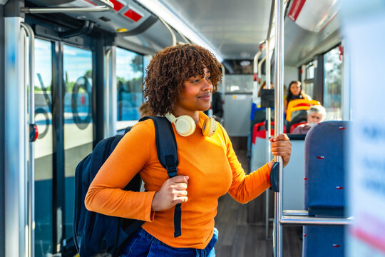 Young woman commuting on bus holding handrail