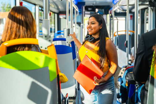Young woman commuting on public bus, holding binder