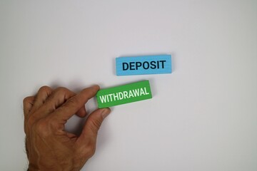 A hand holds a green block labeled “WITHDRAWAL” beside a blue block labeled “DEPOSIT,” representing banking transactions And Finance Concepts. with an white background.