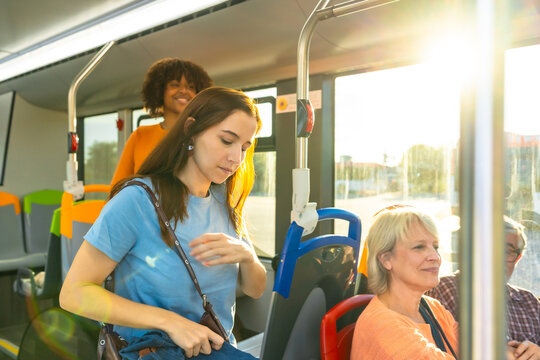 People traveling public transport, sunlight filling bus interior - Powered by Adobe