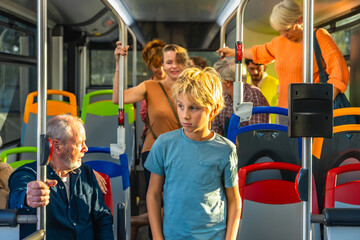 Young boy riding bus with diverse passengers