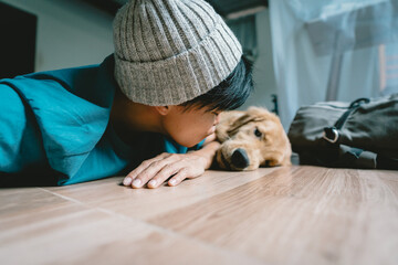 A real Asian man takes a selfie with a year-old golden retriever. The dog is licking its owner's face. Smiling People and fun playing together looking happily at the camera at home Pet and person