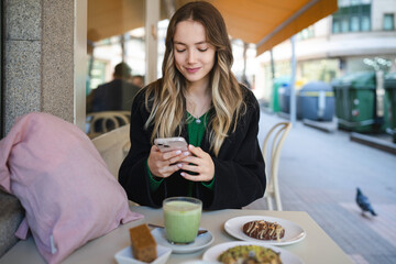 Young woman texting on smartphone at outdoor cafe