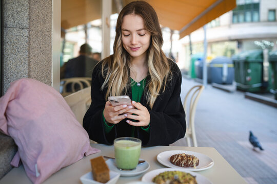 Young woman texting on smartphone at outdoor cafe