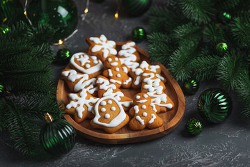 Homemade Decorated Gingerbread Cookies with Icing on Wooden Plate and Pine Decor