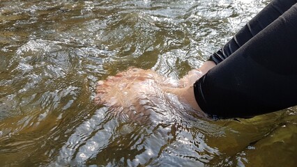 Close up of feet submerged in clear, flowing water, capturing the essence of outdoor relaxation and...