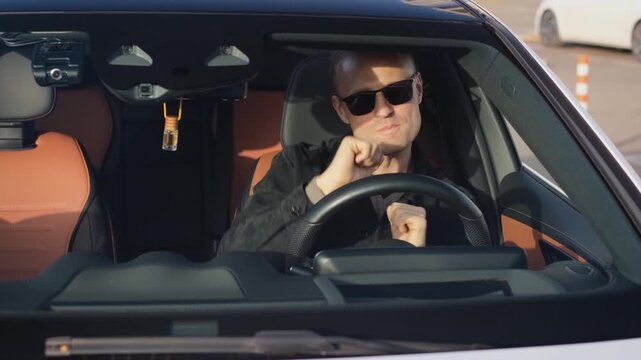 Cheerful adult man singing and moving energetically while sitting in a car