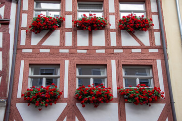 Charming building facade with vibrant red flower boxes adorning windows, showcasing traditional architecture and inviting ambiance, perfect for home decor inspiration and floral design ideas