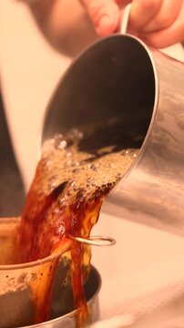 Action of pulling the chai in Singapore and Malaysia cafes where tea is poured from height mixing milk and sugar creating frothy layers inspired by traditional teh tarik coffee preparation
