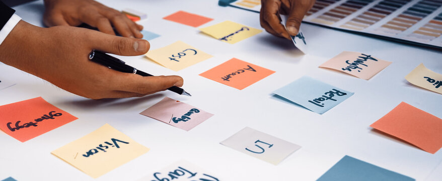 Engaging brainstorming session featuring diverse hands working with colorful sticky notes and a color palette, inspiring creativity and collaboration in a professional setting. SACTR - Powered by Adobe