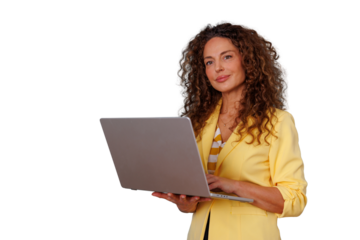 Woman with curly hair holding a laptop, typing, looking at camera with a confident smile, standing. Transparent background