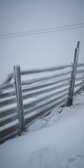 Snowy ski lift machinery in winter fog with frosted fence