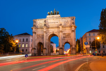 Fototapeta premium Illuminated Siegestor Memorial Arch at Night and Car Light Trails. Munich, Bavaria, Germany