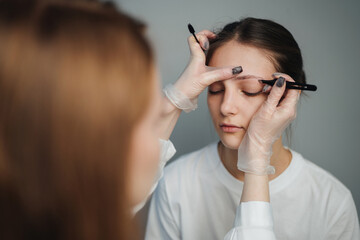 client receiving eyebrow shaping advise, esthetician evaluating symmetry during beauty consultation