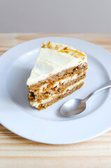 Porción o trozo de torta de zanahoria sobre plato blanco con cucharita de metal. Delicado, tierno y elegante. 
