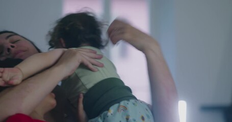 Mother overwhelmed as two young children climb over her with playful intensity, creating chaotic yet affectionate family moment filled with emotion, closeness, and real daily life energy