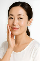スキンケア 透明感のあるツヤ肌のアジア人女性ポートレート 白背景で頬に手を添えるナチュラルな美容イメージ 広告やウェブバナーに使えるコピースペースあり