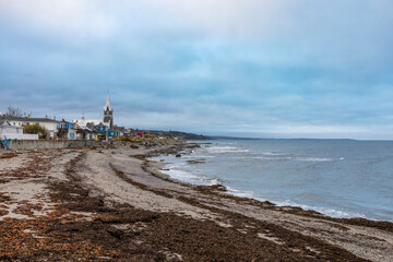 Tranquil scene of Baie-des-Sables, Quebec, featuring a serene coastline with a picturesque village and church.