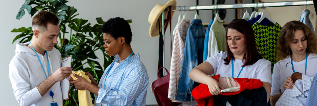 Banner. Group of volunteers, young women, man, sorting clothes in charitable foundation for charity donation, recycling. Concept of textile pollution, conscious consumption. Ecology, sustainable life