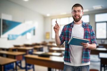 Portrait of confident male teacher standing in classroom and smiling.
