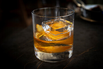 Image of an orange peel in an old fashioned drink with a large ice cube