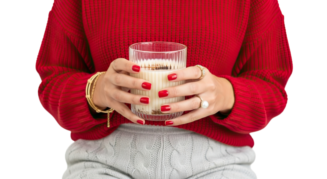 Stylish woman with a festive red manicure wearing a cozy red sweater and gold jewelry holds a glass of a warm, creamy winter drink against an isolated black background - Powered by Adobe
