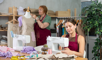 Seamstress works on a sewing machine and stitches fabric against the background of an experienced...