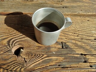 An old aluminum coffee cup on a garden table