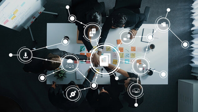 A dynamic top view of a team engaged in a collaborative management session, utilizing digital technology and visual aids to enhance productivity and innovation. Amity