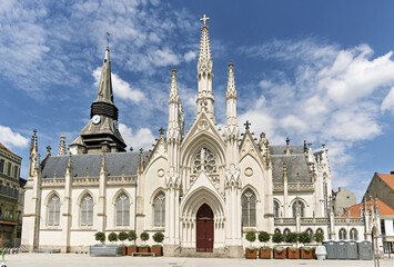 Gothic-style church in Roubaix, France, featuring a symmetrical facade with pointed arches, tall spires, and ornate stone carvings, centered around a large red door