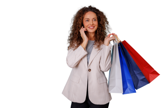 Woman enjoying a shopping spree, holding colorful bags and talking on her smartphone against a transparent background