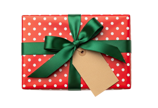 A festive gift box wrapped in red and white polka dot paper with a green satin ribbon and a blank tag, seen from a top-down perspective and isolated on a black background