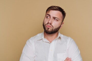 Obraz premium portrait of young thoughtfully pensive man gazes off-camera, reflecting on something meaningful on beige background