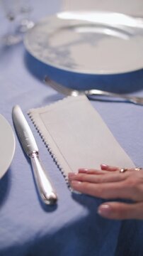 Hand Placing Napkin on Blue Elegant Table Setting