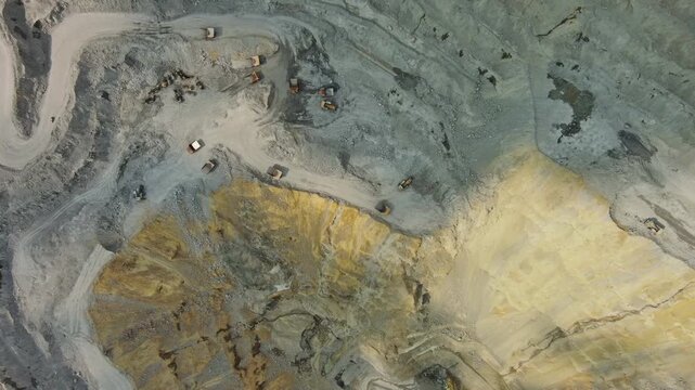 Aerial top view of open pit copper ore mine and heavy mining equipment. Excavator and mining trucks in quarry, 4k