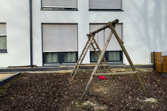 A wooden swing set in a quiet playground near an apartment building