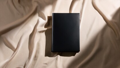 Fototapeta premium Elegant Black Book Mockup On Beige Fabric Background With Soft Light And Shadows