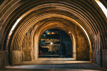 Illuminated Stone Tunnel Leading into a Night City Scene