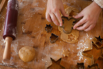 Woman making gingerbread christmas cookies. Hands holding gingerbread dough on rustic table with rolling pin and metal cutters. Winter holiday preparation