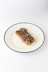 Grilled kofta kebabs with red onion and herbs on plate, isolated on white