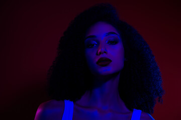 Young stylish woman in neon lighting posing gracefully against a contrasting background showcasing glamour and fashion