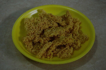 Crispy Fried Soy Snack on Yellow Plate. The porous texture and golden-brown color highlight its crunchy and savory appearance, commonly enjoyed as a light snack